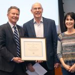 Professor John McGowan, flanked by Chancellor Kevin M. Guskiewicz, left, and his department chair Mary Floyd-Wilson, right, receives the Thomas Jefferson Award at the Feb. 14 Faculty Council meeting. (Jon Gardiner/UNC-Chapel Hill)