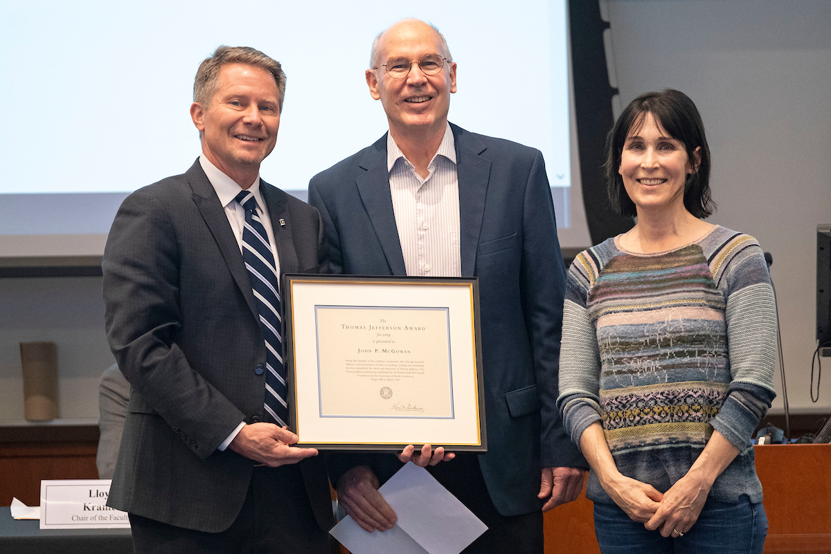 Professor John McGowan, flanked by Chancellor Kevin M. Guskiewicz, left, and his department chair Mary Floyd-Wilson, right, receives the Thomas Jefferson Award at the Feb. 14 Faculty Council meeting. (Jon Gardiner/UNC-Chapel Hill)