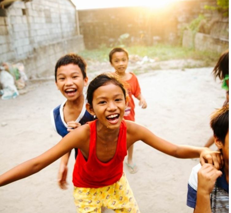 A photo of Filipino children laughing and playing in the street.