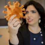 Ronit Freeman holds a 3D printed model of the coronavirus.