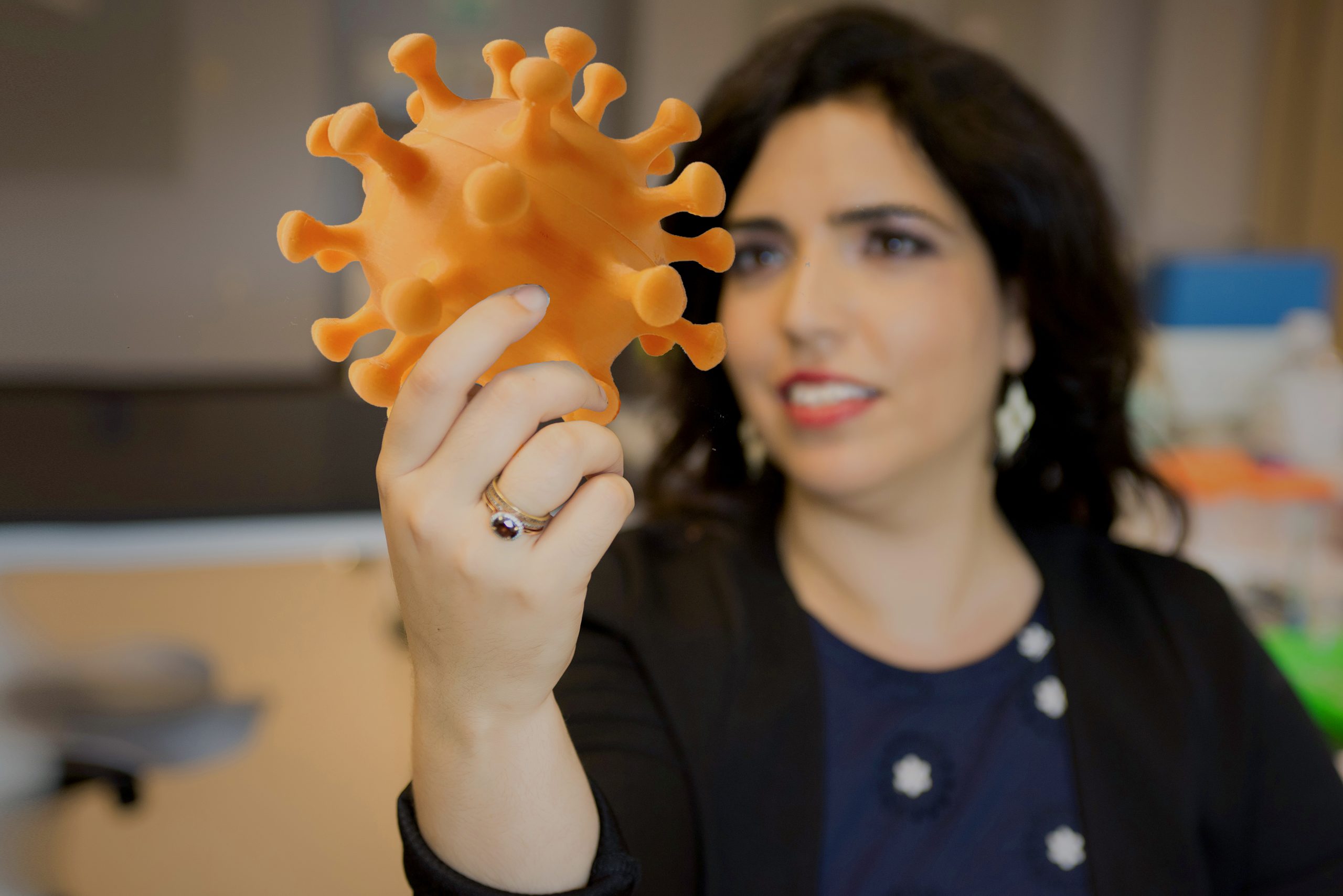 Ronit Freeman holds a 3D printed model of the coronavirus.