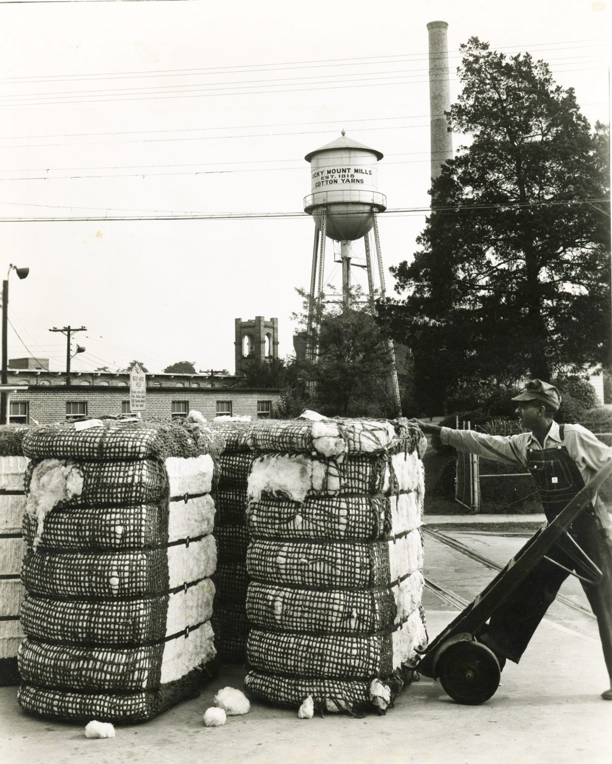 William Henry Summers lifting cotton bales outside the mill with a hand truck. Date unknown.