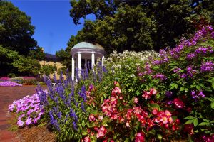 Summer image of the Old Well with colorful flowers in the foreground.