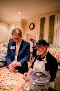 Chancellor Guskiewicz folding dumplings with help from a chef.