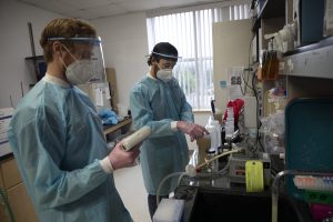 Two graduate students in PPE gear working in a lab