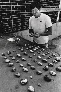 Pete Peterson in 1985 stands in front of a table lined with shells.