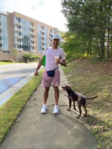 William Sturkey on a walk with a cup of iced coffee in one hand and his dog in the other hand 
