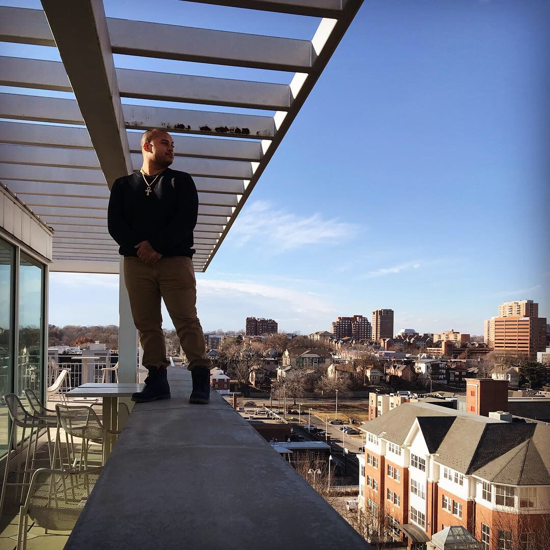 Jordan Davis stands on a concrete wall overlooking campus