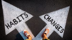 Feet stand in two arrows on the ground; one says "habits"; the other "changes."
