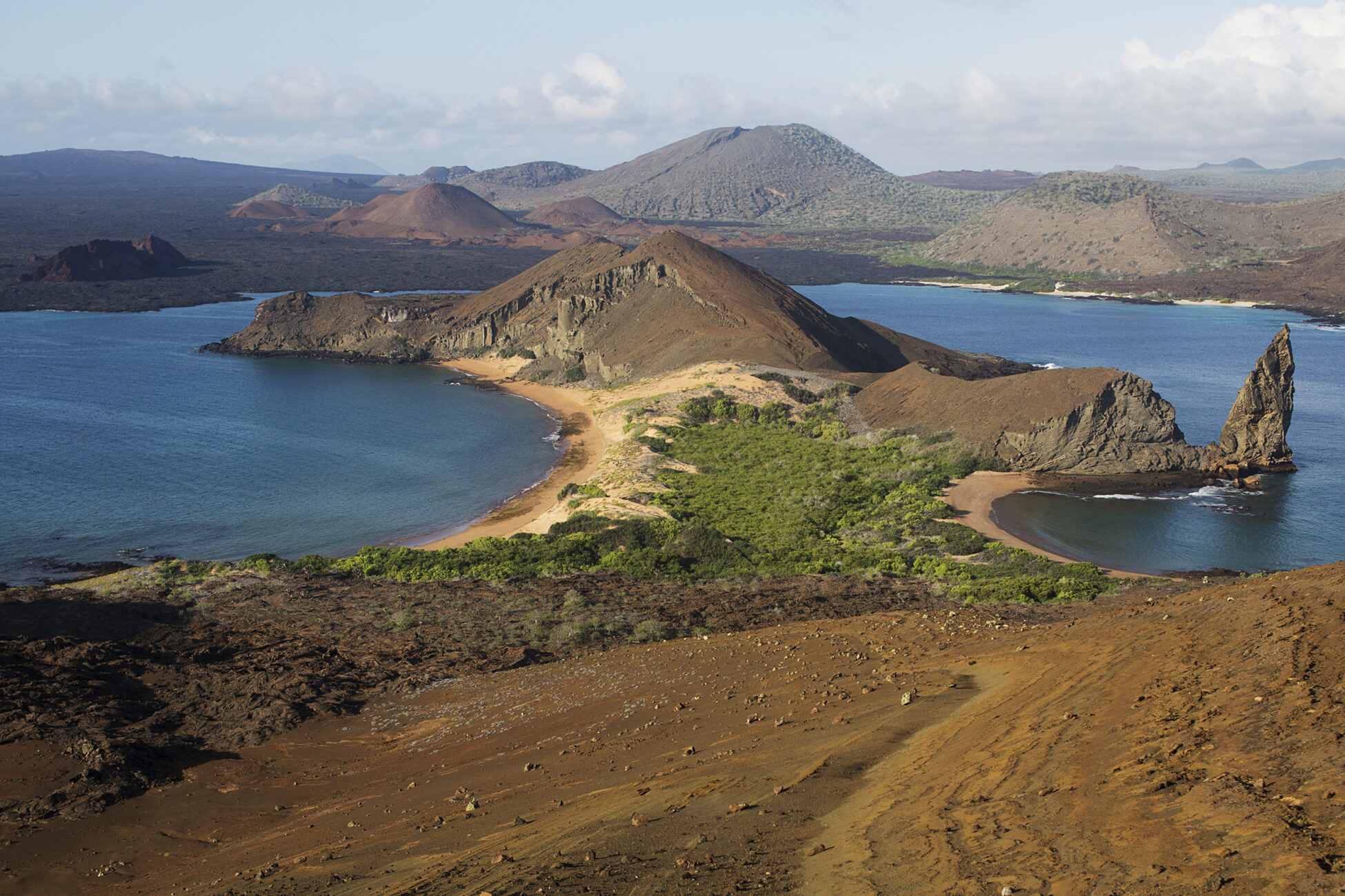 Bartolome Island is one of the most frequently visited sites in the Galapagos archipelago. (photo by Megan May). Photo is a wide angle view of the island, with mountains and the ocean.