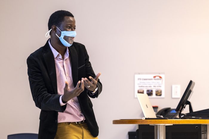 “There is a big difference between teaching in person and online. In person is easier,” said Samba Camara, shown here teaching an Introduction to Africa course. (Jon Gardiner/UNC-Chapel Hill). The professor is shown with a mask at the front of the classroom.