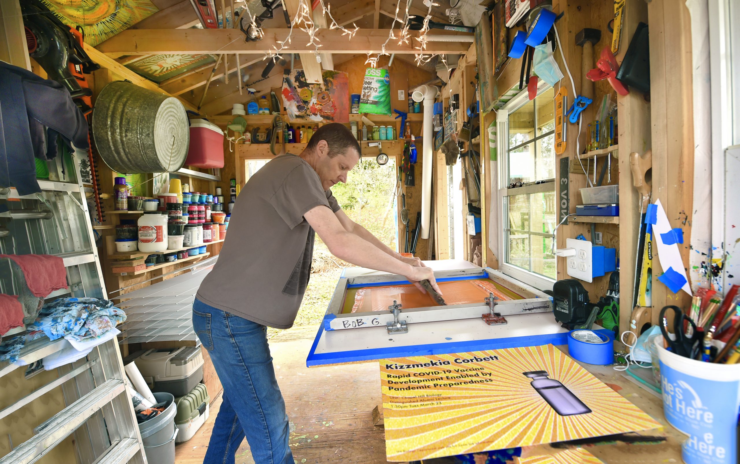 Goldstein demonstrates how to screen print a poster using the color orange.