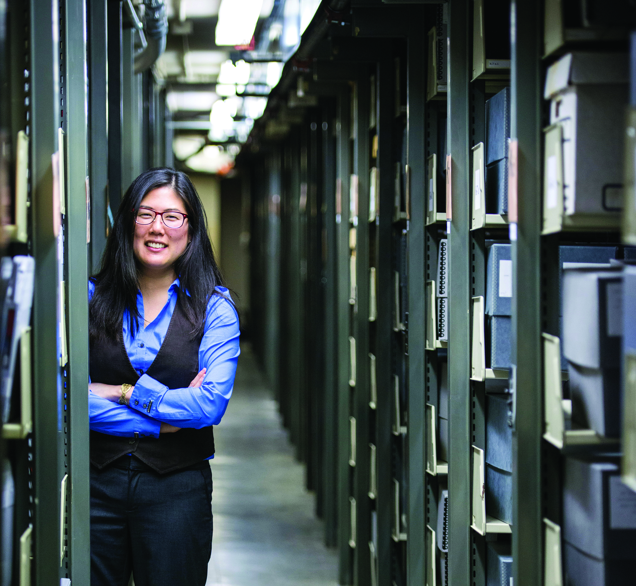 Heidi Kim in the library stacks peers around the corner. (photo by Steve Exum)