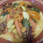 a plate of Moroccan couscous with vegetables on top.
