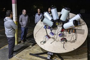 A group of people standing around a telescope prototype