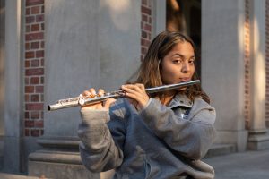Ashley Medina playing flute in front of the bell tower