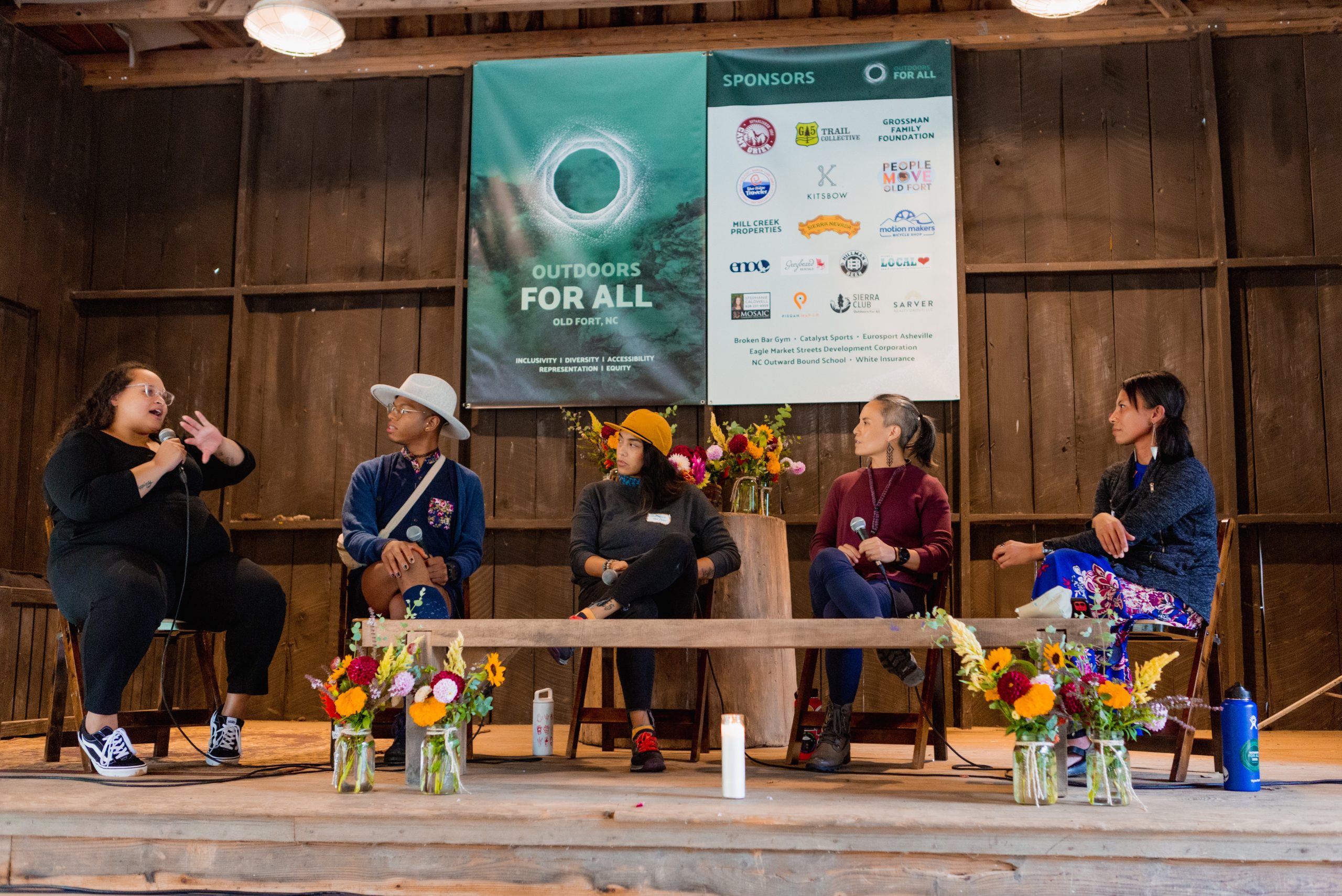 Speakers sit on a stage discussing topics at the "Outdoors for All" Summit.