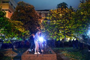 UNC students dance in the sculpture garden outside Hamilton Hall at night.