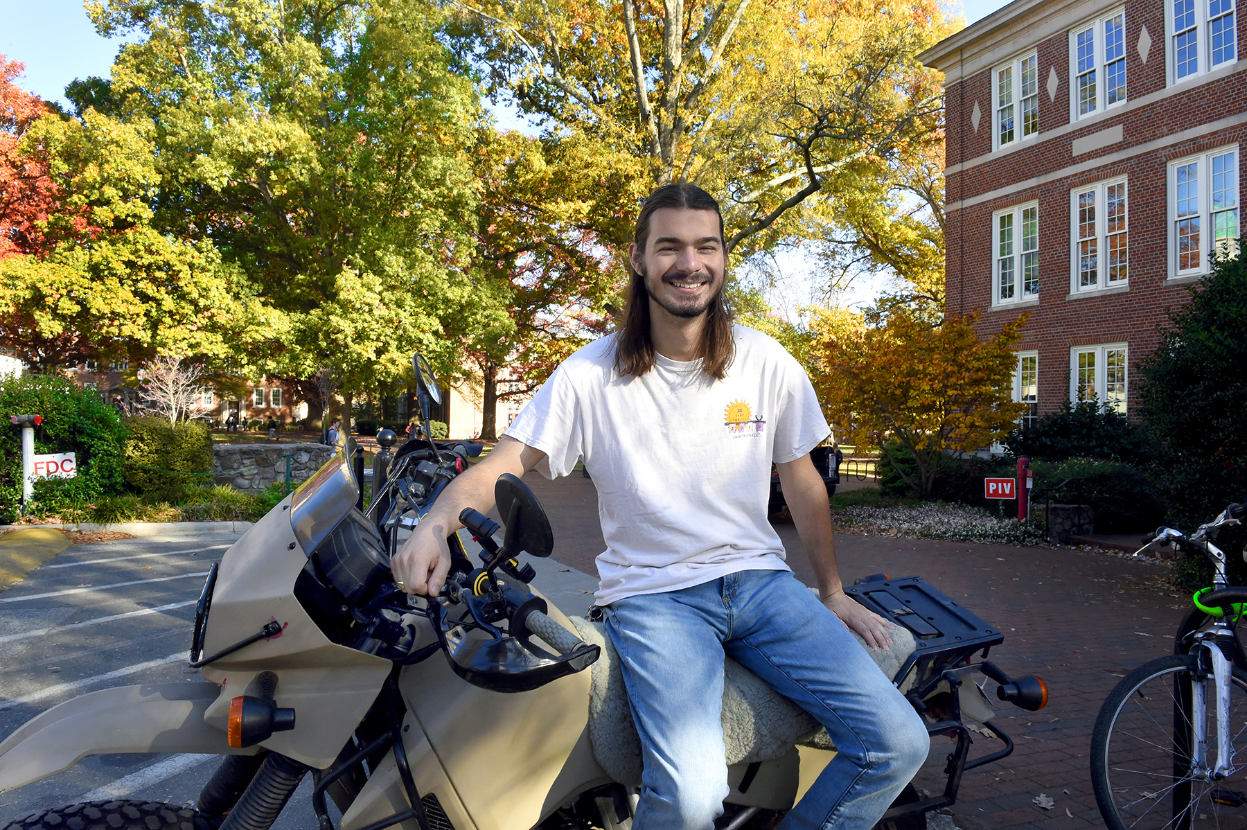 Elliot Carey sits on his motorcycle on campus.