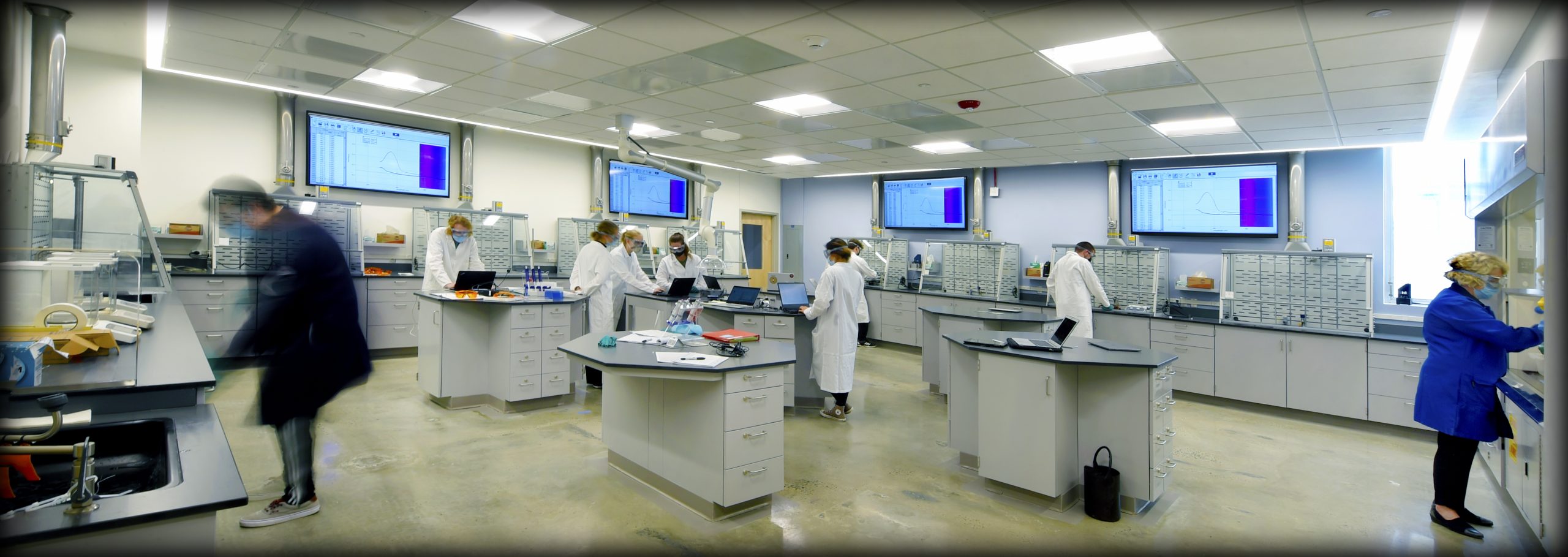 A panoramic shot of the new Lab of the Future, with lab tables in the center. People in lab coats work at the tables.