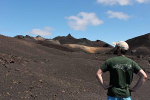 A researcher standing and staring at a volcano