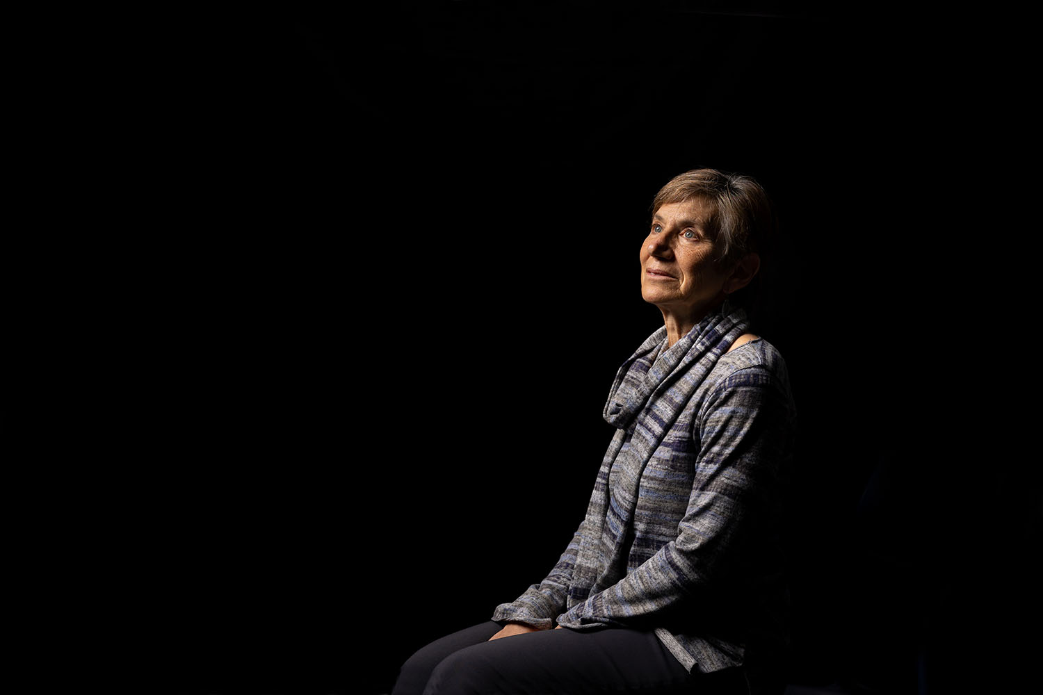 Professor of philosophy Susan Wolf sits against a pitch-black background looking to her left..