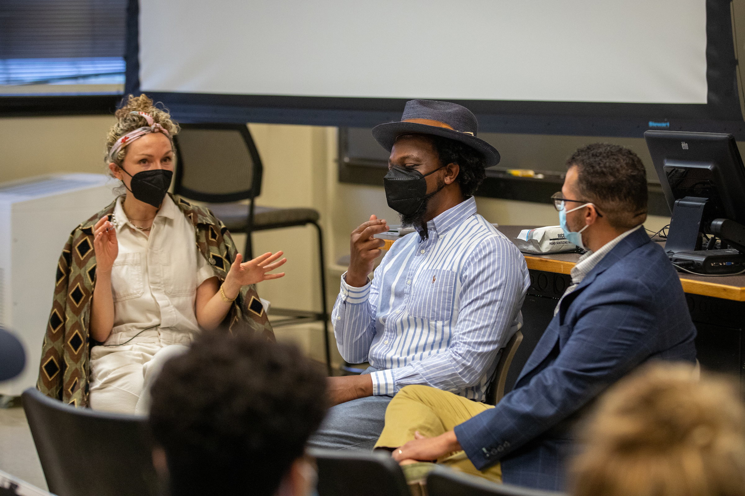 Shuford innovators sit around a classroom talking, with masks on.