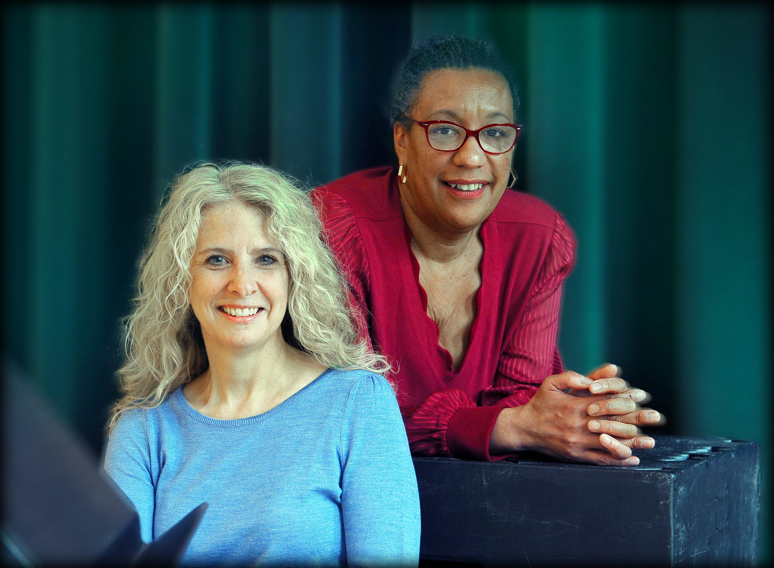Coastal scientist Laura Moore (left) and dramatic art faculty member Kathryn Hunter-Williams in front of a black curtain in a room in the Center for Dramatic Art.