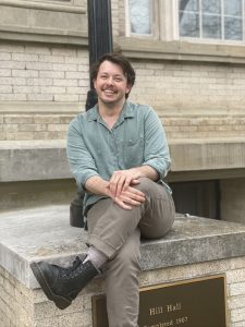 Elias Gross sits on the steps of Hill Hall.
