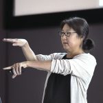 Maya Lin gestures at the audience from the stage.