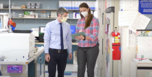 Two people with masks on walking in a lab