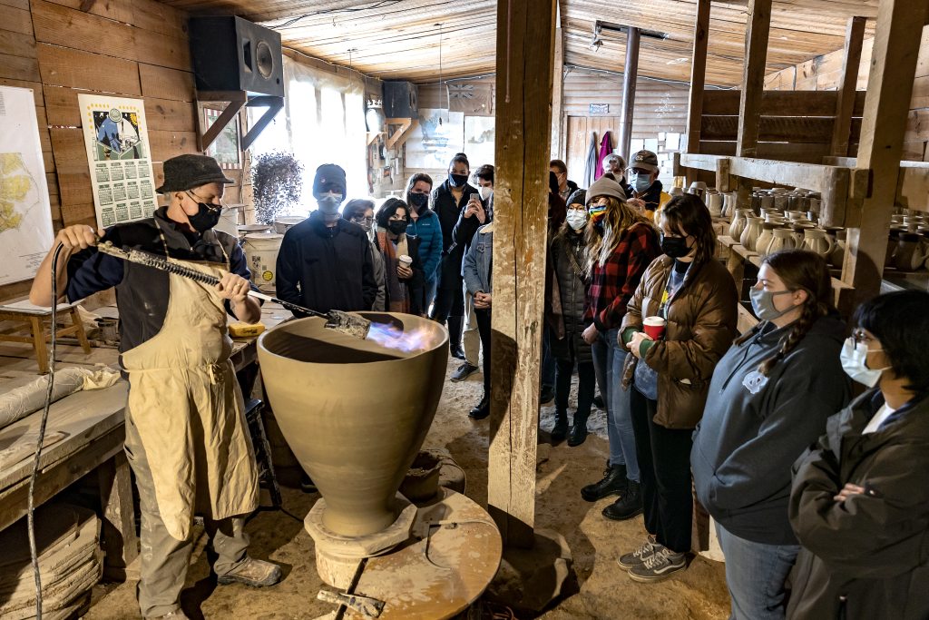 Mark Hewitt demonstrates how he creates tall pots by using fire to dry the clay quickly before it collapses under its own weight. (Johnny Andrews/UNC-Chapel Hill)