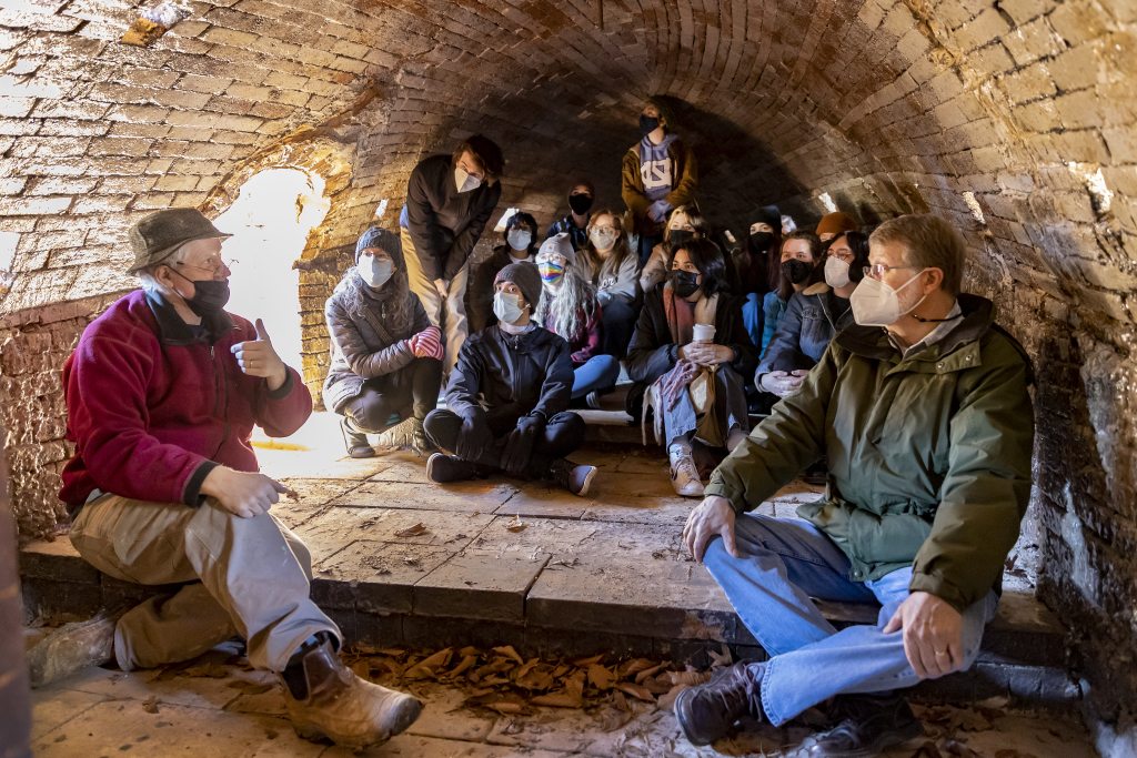 Hewitt (left), Carolina archaeologist Steve Davis (right) and the students gather inside the kiln to discuss the temperatures at which pottery can be fired. (Johnny Andrews/UNC-Chapel Hill)