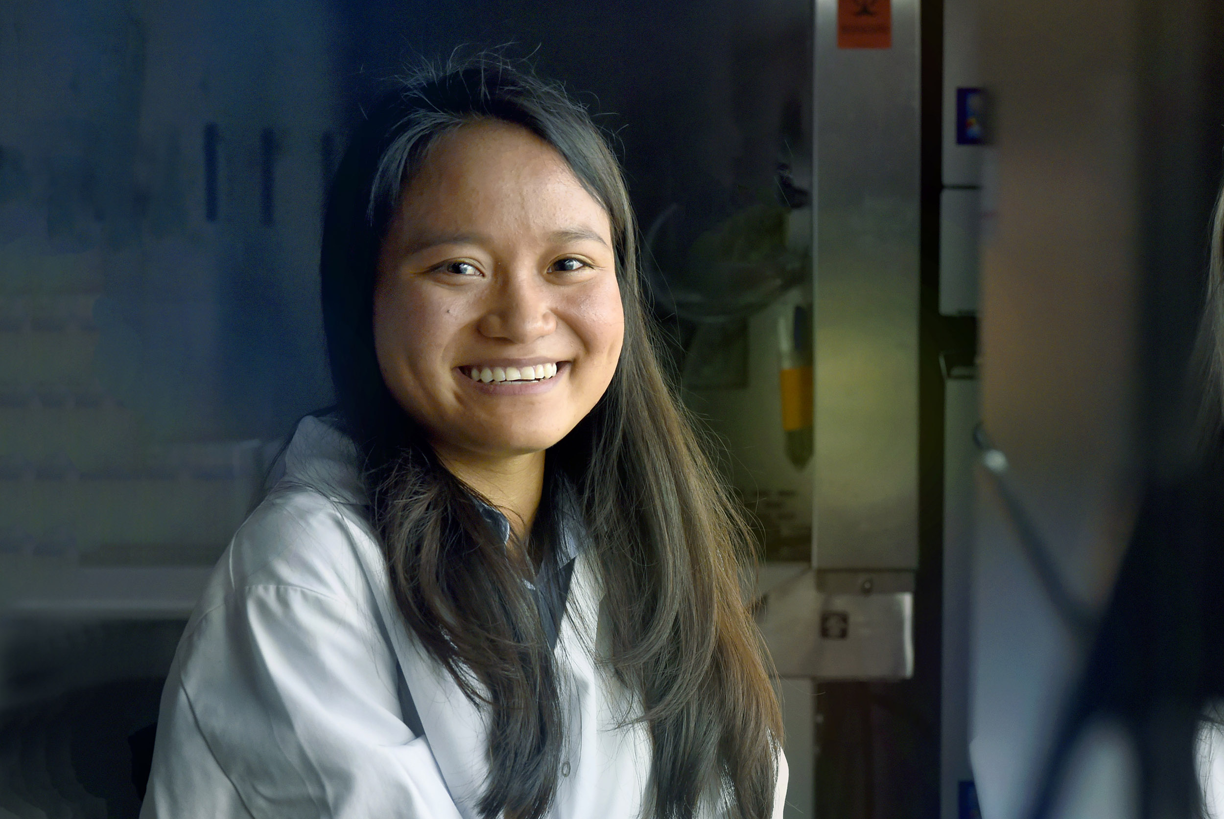 Thidar Aye in her lab coat smiles at the camera.