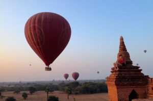 A hot air balloon in the sky in Myanmar takes off over a temple.