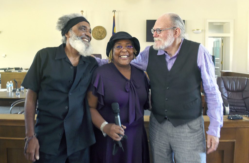 Three people stand together smiling after the performance in the Warren County Courthouse.