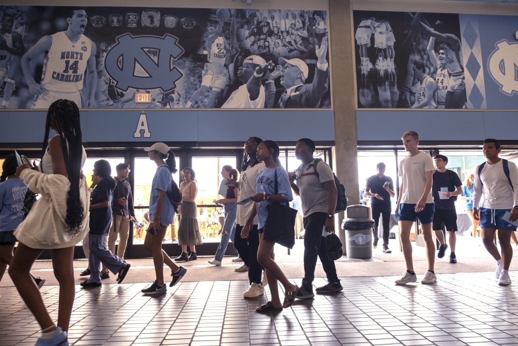 Students walk in a single file in the Dean Smith Center lobby.
