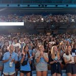 Students in Tar Heel attire gather in the Dean Smith Center for convocation.
