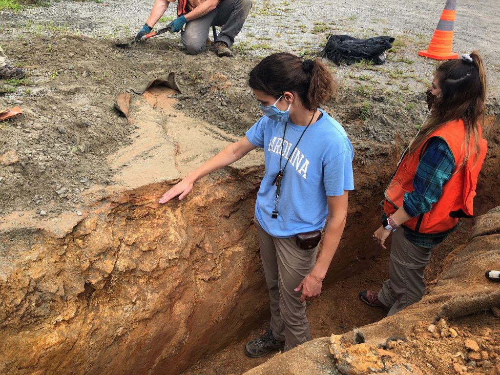 Earth, marine and environmental sciences graduate student Sarah Wells-Hull, left, puts her hand on the Little River fault after an earthquake at Sparta, North Carolina, ruptured the ground in 2020. Ashley Lynn, right, works in the trench dug to expose the fault.