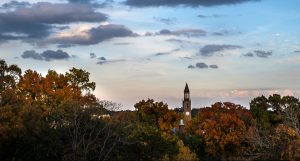 The bell tower in the distance surrounded by fall foliage.