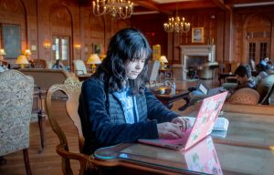Megan Castle types on her laptop at a desk in Graham Memorial lounge.