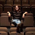 Bronwyn White sits in an empty row of seats in a theater.