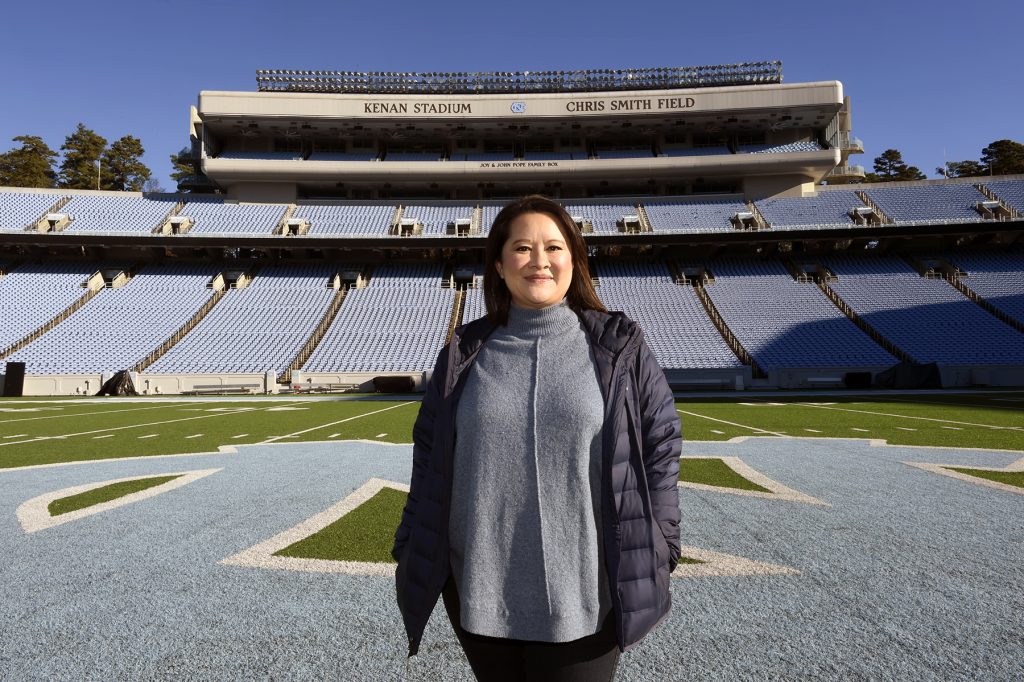 Angela Nguyen stands, smiling, in the middle of Kenan Stadium.