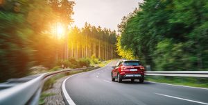 Stock image of a car driving down an interstate lined with trees.