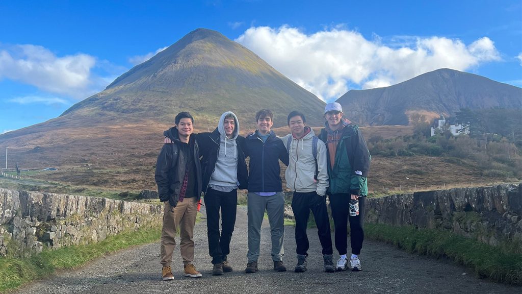Jackson Holmes and four other study abroad students huddle together for a photo in front of mountain landscape.