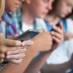 Closeup of a group of teens using their cell phones.