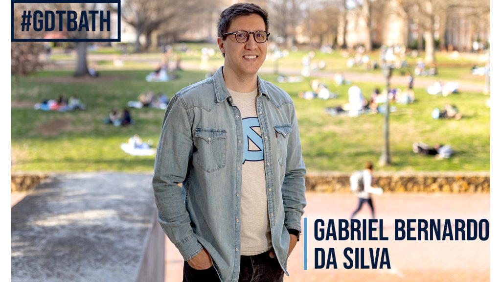 Waist-up shot of Gabriel Bernardo da Silva, UNC’s campus out of focus in the background. Features the hashtag “#GDTBATH” and da Silva’s name in navy lettering.