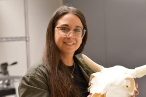Katie Tardio holds the bones of an animal head.