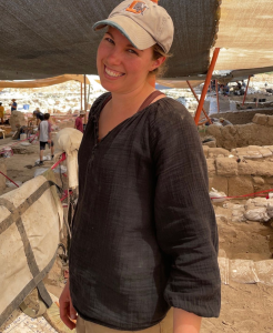 Jocelyn stands outside wearing a ball cap at the Huqoq dig site.