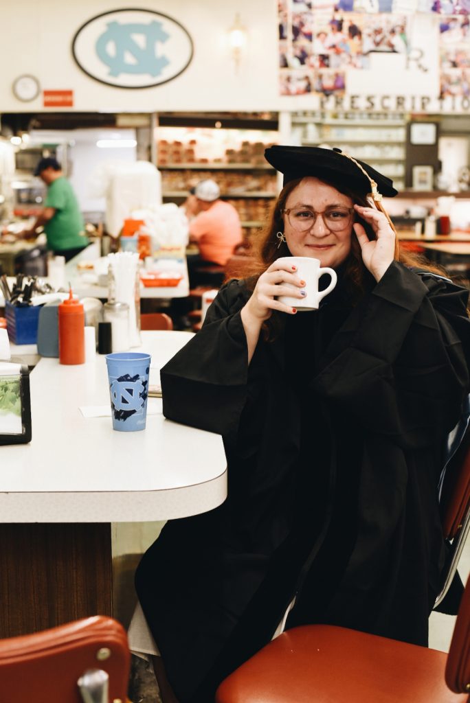 KC Hysmith sits in Suttons Drug Store in chapel Hill, wearing her cap and gown.